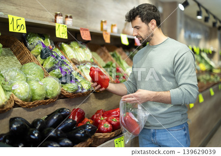 Male employees in uniform holding fresh bell pepper in grocery shop Male employees in uniform holding fresh bell pepper in grocery shop 139629039