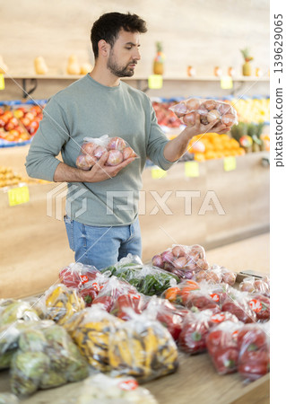 Customer in a supermarket is standing in the department with vegetables Customer in a supermarket is standing in the department with vegetables 139629065