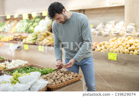 Man holding bag to weigh nuts before buying in farm store Man holding bag to weigh nuts before buying in farm store 139629074