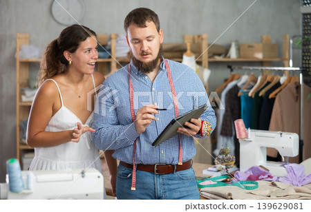 Male dressmaker discussing with girl the sketch on tablet 139629081
