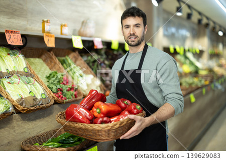 supermarket seller holds a basket of red bell peppers supermarket seller holds a basket of red bell peppers 139629083