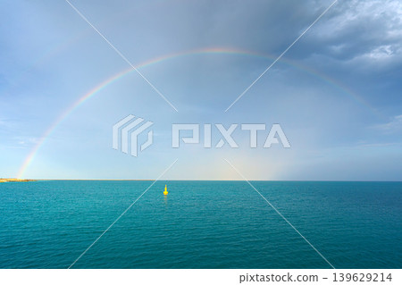 Sir Bani Yas island, United Arab Emirates - Jan 18 2024, aerial panoramic sea view with cloudy sky and rainbow, yellow buoy on the water surface, at daytime, Sir Bani Yas, UAE Sir Bani Yas island, United Arab Emirates - Jan 18 2024, aerial panoramic sea view with cloudy sky and rainbow, yellow buoy on the water surface, at daytime, Sir Bani Yas, UAE 139629214