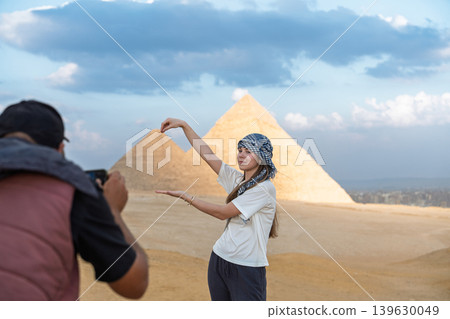 Young woman poses for a photograph with the Great Pyramids of Giza in Egypt, capturing travel 139630049