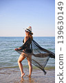 Woman walking in shallow sea water with flowing sheer cover up 139630149