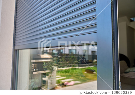 Partially closed roller shutter on modern home window Partially closed roller shutter on modern home window 139630389