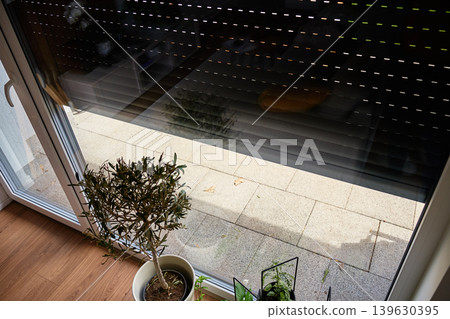 Partially lowered roller shutter over glass patio door Partially lowered roller shutter over glass patio door 139630395