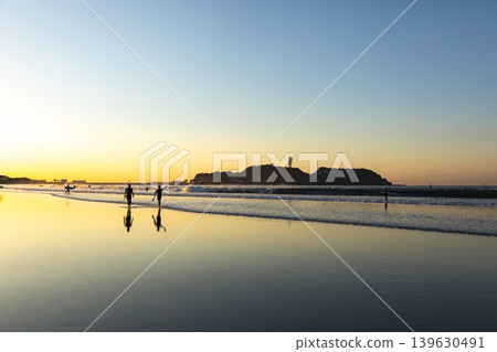 湘南久沼海灘:江之島和衝浪者從海中浮現的身影。 湘南久沼海灘:江之島和衝浪者從海中浮現的身影。 139630491