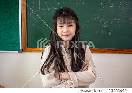 Portrait of confident elementary school child standing in classroom with arms crossed. education self-confidence, leadership, and childhood development concept. Portrait of confident elementary school child standing in classroom with arms crossed. education self-confidence, leadership, and childhood development concept. 139630604