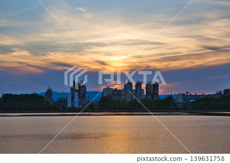 A train running through an industrial area at dusk. A train running through an industrial area at dusk. 139631758