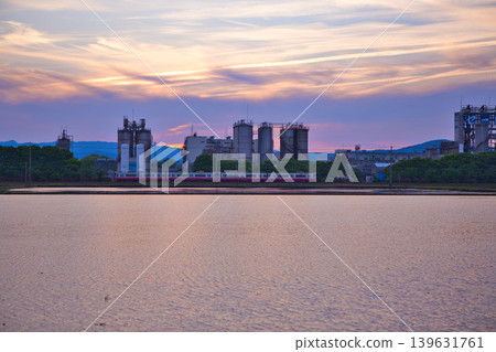 A train running through an industrial area at dusk. A train running through an industrial area at dusk. 139631761