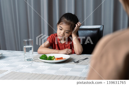Mother is telling her cute kid eat useful vegetables but the child refuses to eat. 139631765