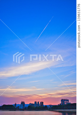 A train running through an industrial area at dusk. A train running through an industrial area at dusk. 139631776
