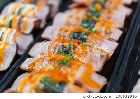 Premium sushi rolls topped with sauce seaweed and fish roe served on black tray featuring fresh Japanese cuisine and gourmet seafood presentation 139632980