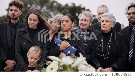 Funeral, cemetery and family with American flag for veteran for respect, ceremony and memorial service. Sad, depression and people by coffin in graveyard for military hero, army and soldier mourning 139634555