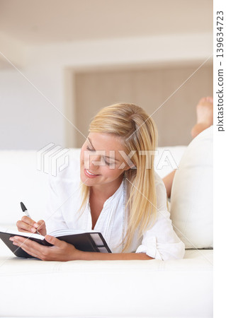 Writing, notebook and planning with woman on sofa for goals, diary and schedule. Calendar, relax and list with female person and journal in living room of home for self care, reflection and idea Writing, notebook and planning with woman on sofa for goals, diary and schedule. Calendar, relax and list with female person and journal in living room of home for self care, reflection and idea 139634723