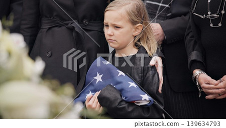 Funeral, cemetery and child with American flag for veteran for respect, ceremony and memorial service. Family, depression and sad girl by coffin in graveyard mourning military, army and soldier hero 139634793