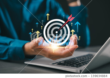 Target business objective growth and goal through businessman holding virtual target icon with rising arrows above laptop, hitting marketing target for company success and future vision Target business objective growth and goal through businessman holding virtual target icon with rising arrows above laptop, hitting marketing target for company success and future vision 139634864
