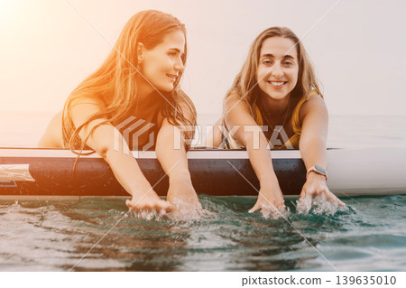 Women Paddleboard Ocean Water Sport Smiling - Two women on a paddleboard in the ocean, smiling and splashing water. Women Paddleboard Ocean Water Sport Smiling - Two women on a paddleboard in the ocean, smiling and splashing water. 139635010