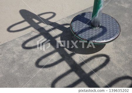Interesting shadows of playground equipment cast on the ground in a park on a sunny day. 139635202