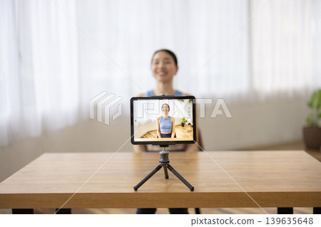 一位身穿瑜珈服的中年日本女性正在平板電腦前說話。 139635648