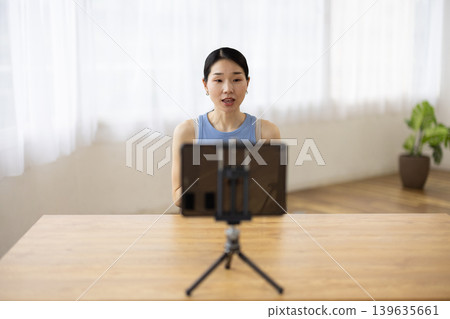 一位身穿瑜珈服的中年日本女性正在平板電腦前說話。 139635661