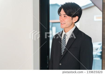 Smiling young Asian man in a suit returning home Smiling young Asian man in a suit returning home 139635820