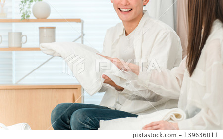 一對面帶微笑的夫婦在客廳裡疊衣服 一對面帶微笑的夫婦在客廳裡疊衣服 139636011