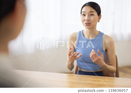A middle-aged Japanese woman in yoga wear, smiling and talking. A middle-aged Japanese woman in yoga wear, smiling and talking. 139636057