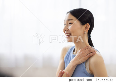 A middle-aged Japanese woman in yoga wear, smiling and talking. 139636058