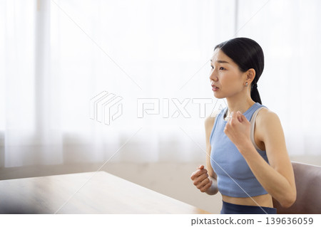 A middle-aged Japanese woman in yoga wear, smiling and talking. A middle-aged Japanese woman in yoga wear, smiling and talking. 139636059