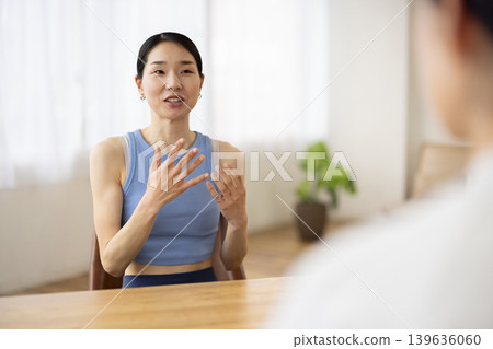A middle-aged Japanese woman in yoga wear, smiling and talking. 139636060