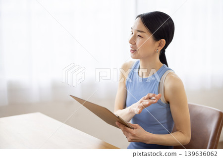 A middle-aged Japanese woman in yoga wear, smiling and talking. 139636062