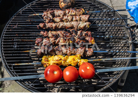 Grilled lamb kebabs cooking on skewers over charcoal barbecue grill outdoors. Grilled lamb kebabs cooking on skewers over charcoal barbecue grill outdoors. 139636294