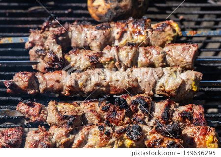 Grilled lamb kebabs cooking on skewers over charcoal barbecue grill outdoors. Grilled lamb kebabs cooking on skewers over charcoal barbecue grill outdoors. 139636295