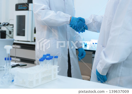 Scientists Shaking Hands in Laboratory Representing Teamwork, Success, and Medical Research Collaboration. Scientists Shaking Hands in Laboratory Representing Teamwork, Success, and Medical Research Collaboration. 139637009