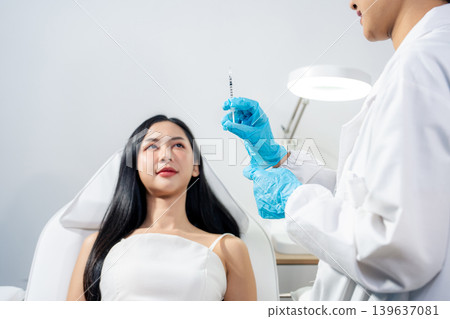 Asian woman consulting with a doctor at a modern aesthetic clinic for facial treatment. 139637081