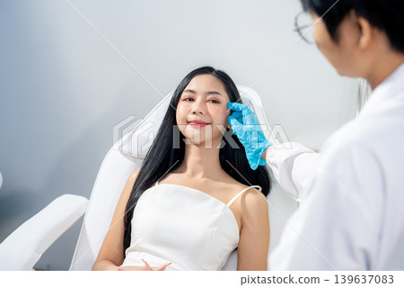 Asian woman consulting with a doctor at a modern aesthetic clinic for facial treatment. Asian woman consulting with a doctor at a modern aesthetic clinic for facial treatment. 139637083