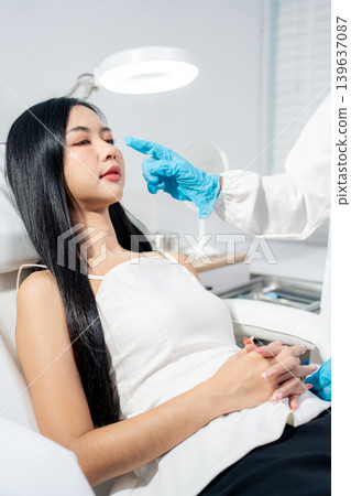 Asian woman consulting with a doctor at a modern aesthetic clinic for facial treatment. Asian woman consulting with a doctor at a modern aesthetic clinic for facial treatment. 139637087
