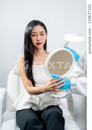 Asian woman consulting with a doctor at a modern aesthetic clinic for facial treatment. 139637102
