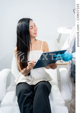 Asian woman consulting with a doctor at a modern aesthetic clinic for facial treatment. Asian woman consulting with a doctor at a modern aesthetic clinic for facial treatment. 139637103