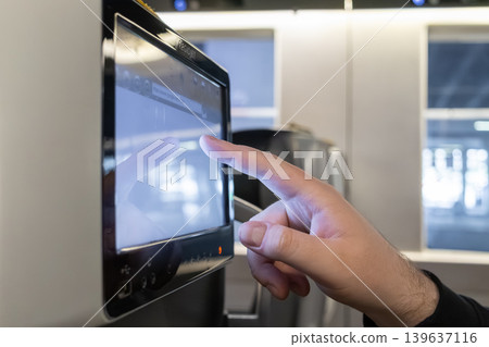 A passenger touches a multimedia touchscreen on a train to represent modern digital travel connectivity, public transit entertainment systems, and user interaction with information technology A passenger touches a multimedia touchscreen on a train to represent modern digital travel connectivity, public transit entertainment systems, and user interaction with information technology 139637116