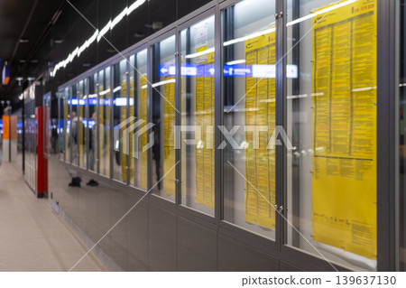 Public transport schedules are printed on yellow paper inside glass cabinets at a modern railway station to assist passengers with travel information, commuter logistics, and urban navigation Public transport schedules are printed on yellow paper inside glass cabinets at a modern railway station to assist passengers with travel information, commuter logistics, and urban navigation 139637130