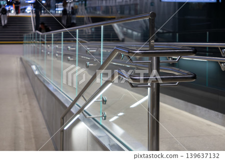 Modern stainless steel railing with tempered glass panel in a contemporary train station terminal, highlighting architectural design, structural safety, and efficient public transport access Modern stainless steel railing with tempered glass panel in a contemporary train station terminal, highlighting architectural design, structural safety, and efficient public transport access 139637132