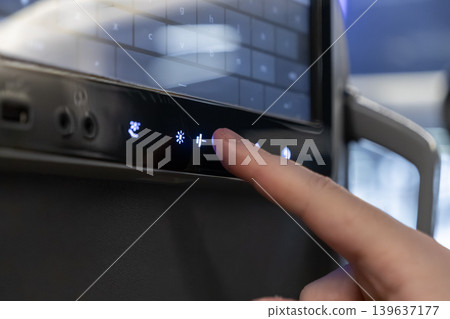 A passenger finger presses an airline seat adjustment button on a digital entertainment console screen, reflecting the modern travel experience with interactive cabin technology for comfort A passenger finger presses an airline seat adjustment button on a digital entertainment console screen, reflecting the modern travel experience with interactive cabin technology for comfort 139637177