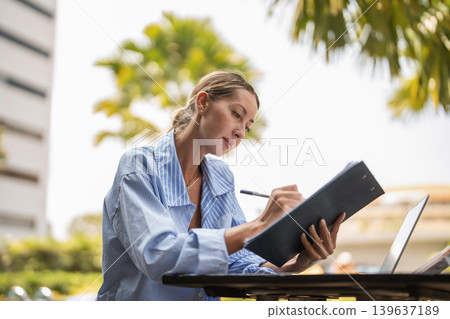 Female entrepreneur working remotely. Small business owner managing documents, laptop, and online success. Female entrepreneur working remotely. Small business owner managing documents, laptop, and online success. 139637189