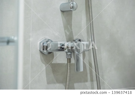 Modern chrome shower faucet with lever handle installed on a light tiled wall, representing luxury bathroom design, water conservation, and home improvement for interior renovation Modern chrome shower faucet with lever handle installed on a light tiled wall, representing luxury bathroom design, water conservation, and home improvement for interior renovation 139637418