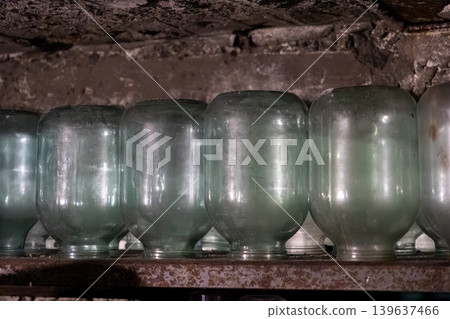 Row of empty glass jars lined up on a dusty shelf in a rustic cellar, evoking a sense of historical food preservation, domestic tradition, and preparation for seasonal harvest Row of empty glass jars lined up on a dusty shelf in a rustic cellar, evoking a sense of historical food preservation, domestic tradition, and preparation for seasonal harvest 139637466