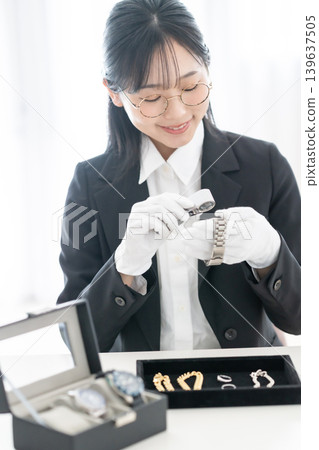An appraiser verifies the authenticity of a precious metal watch; his hand holds a magnifying glass; men's watch; asset value appraisal. 139637505