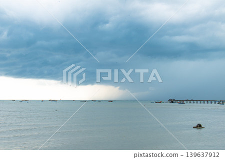 Storm cloud over calm sea, distant boat and pier on horizon Storm cloud over calm sea, distant boat and pier on horizon 139637912