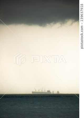 Storm cloud over distant ship on sea, moody seascape with hazy horizon and dark water Storm cloud over distant ship on sea, moody seascape with hazy horizon and dark water 139637918